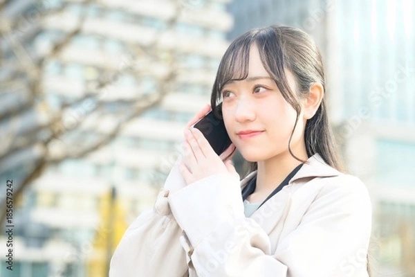 Fototapeta オフィス街でスマホを使用する20代のビジネスウーマン