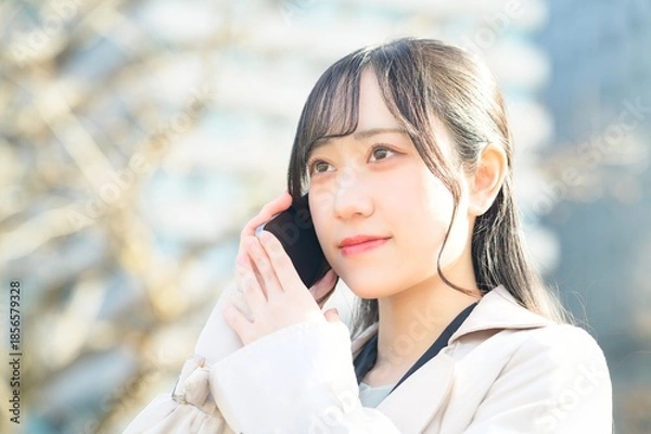 Fototapeta オフィス街でスマホを使用する20代のビジネスウーマン