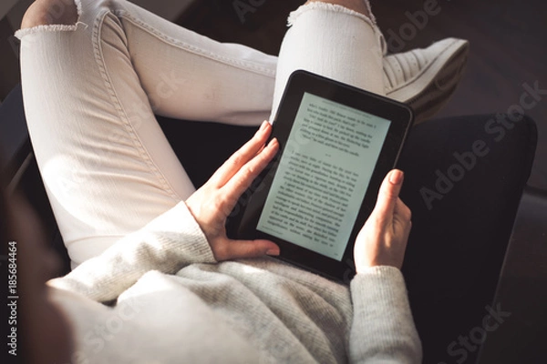 Obraz Woman sitting by the window with an e-book