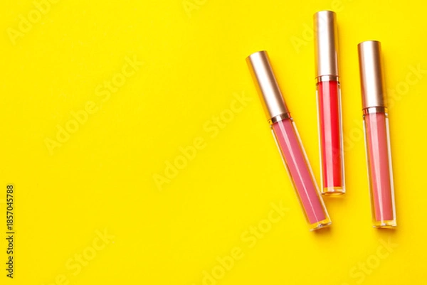 Obraz Different lip glosses on yellow background, flat lay. Space for text