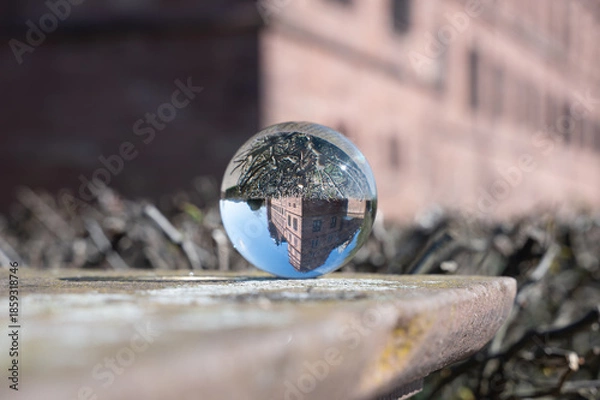 Obraz A glass sphere reflecting a castle; the sphere rests on a wall.