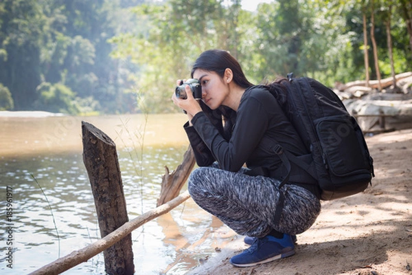 Fototapeta Asian woman backpack taking a photo with mirrorless camera