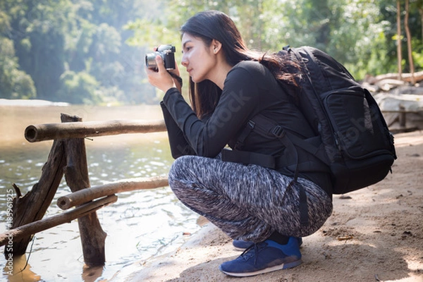 Fototapeta Asian woman backpack taking a photo with mirrorless camera