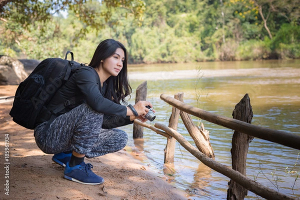 Fototapeta Asian woman backpack taking a photo with mirrorless camera
