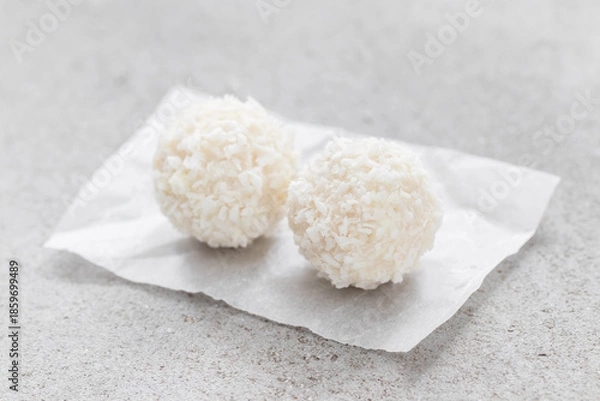 Obraz Two Coconut candy balls. On paper. Light background. Close-up