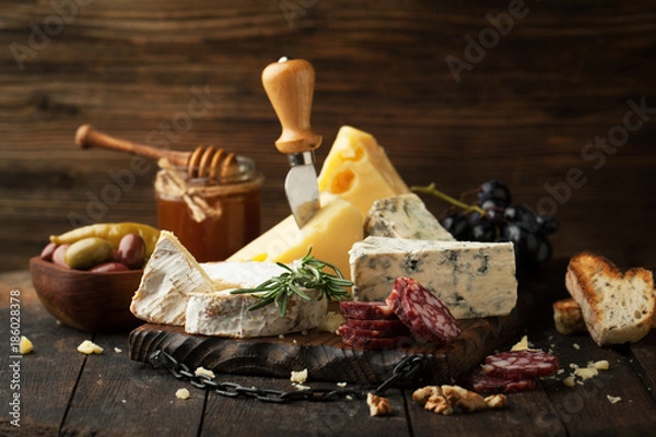 Fototapeta Assorted cheeses with grapes, nuts and rosemary