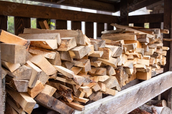 Obraz 屋外の棚に積み重ねられた乾燥した薪の山