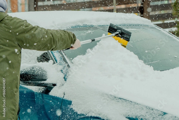 Obraz Brushing Snow Off a Car Windshield in Winter