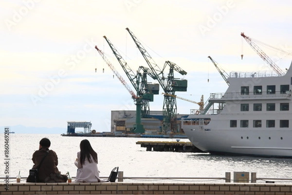 Obraz 神戸メリケンパークの岸壁に座り海を眺める男女