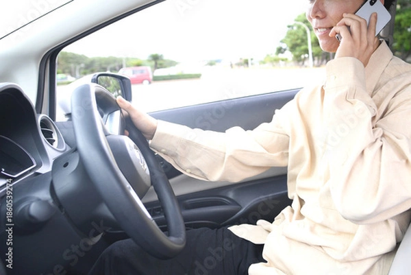 Obraz スマホ通話をしながら車を運転する若いアジア人男性