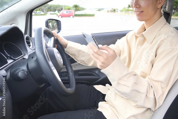 Obraz スマホ通話をしながら車を運転する若いアジア人男性