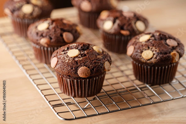 Obraz Chocolate muffins with white and milk chocolate chips on wooden table. Selective focus. Home baking concept, recipe.