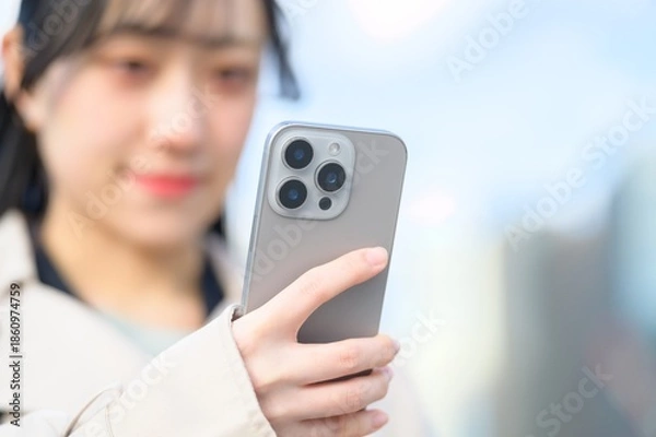 Obraz オフィス街でスマホを使用する日本人ビジネスウーマン