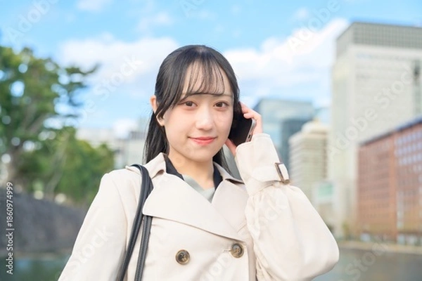 Obraz オフィス街でスマホを使用する日本人ビジネスウーマン