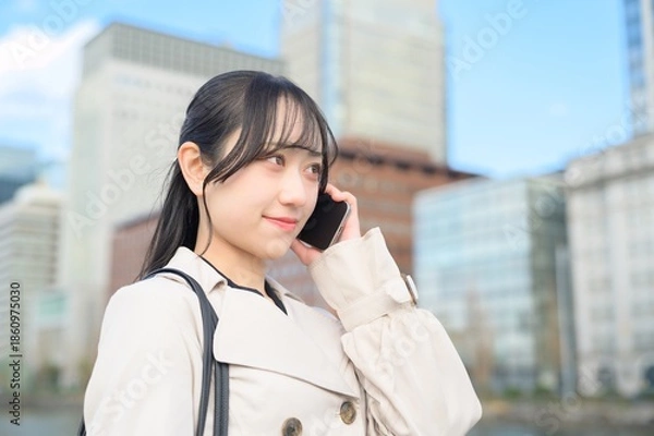 Obraz オフィス街でスマホを使用する日本人ビジネスウーマン