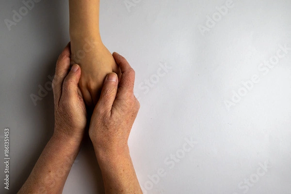 Obraz Elderly Hands Protecting Young Arm