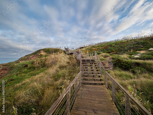 Obraz Wooden boardwalk steps winding up coastal hill in Portugal