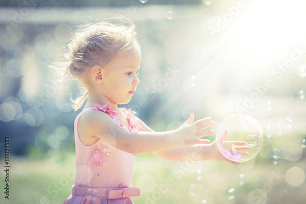 Obraz Mała dziewczynka łapie bańki mydlane w letnim parku