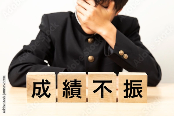 Fototapeta 「成績不振」と書かれたブロックと悩む男子学生