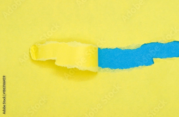 Obraz torn yellow paper on blue background