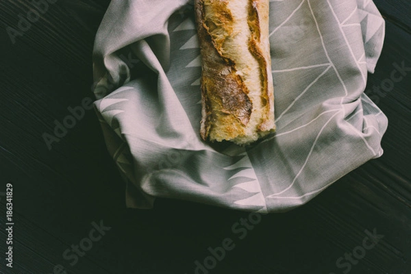 Obraz Fresh bread french baguette on a cloth and black wood, moody dark food photography