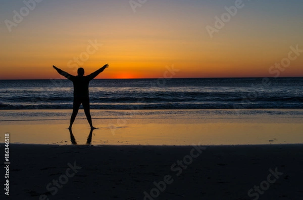 Fototapeta young woman watching the sunrise over the ocean