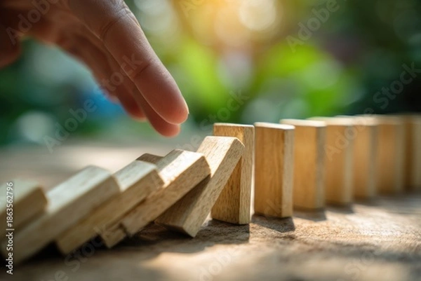 Obraz Hand pushing domino, triggering a chain reaction