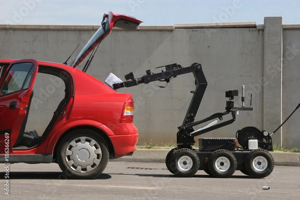 Fototapeta Terrorism. Bomb. Robot. A robot disarm a bomb inside a car of terrorists. Bomb squad robot. 