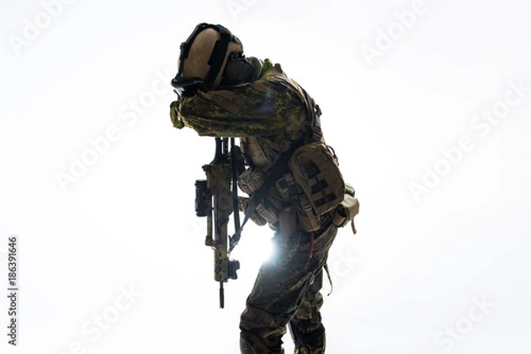 Fototapeta Defender shutting appearance by arm while keeping assault rifle. Camouflage concept. Isolated