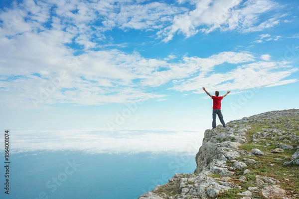 Fototapeta Man on sea cliff edge and blue sky at spring day.
