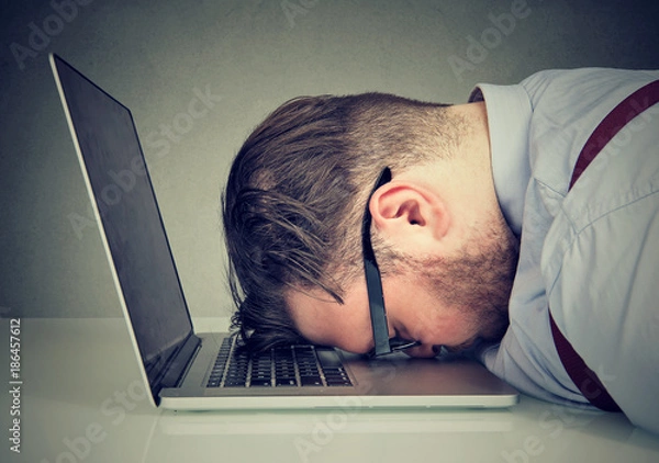 Obraz Przepracowany mężczyzna leżący na laptopie