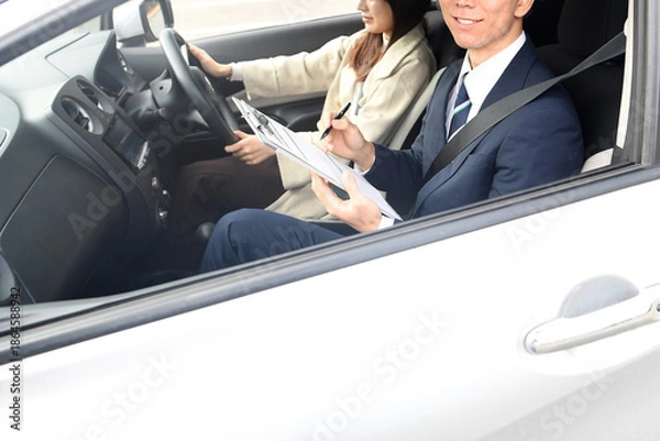 Obraz 自動車教習所で指導するアジア人の男性教官と若い女性