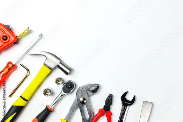 Fototapeta Top view of Working tools,wrench,socket wrench,hammer,screwdriver,plier,electric drill,tape measure,machinist square and safety glasses on white background.flat lay design for construction concept