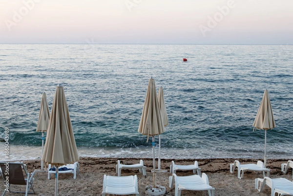 Obraz Empty beach with closed umbrellas at dusk