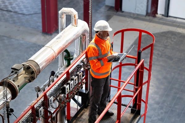 Obraz Engineer checking industrial plant system on laptop