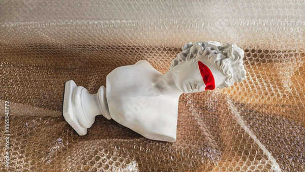Obraz A white classical plaster bust sculpture resting on a transparent bubble wrap packaging texture background 