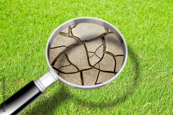 Fototapeta Cracked ground seen through a magnifying glass - The effects of drought - Concept image