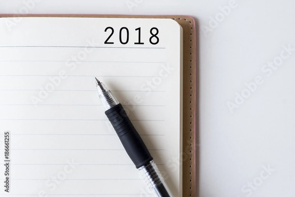 Fototapeta Conceptual,notebook on a white table. open diary and pen with 2018 words