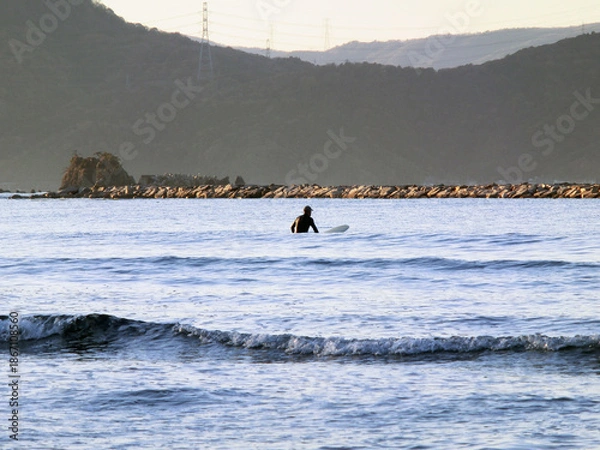 Fototapeta 波間のサーファーのシルエットと背後に山々