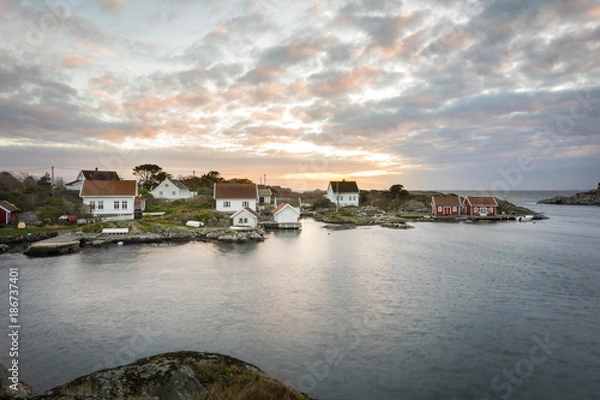 Fototapeta Lillesand, Norway - November 7, 2017: Ulvoysund, ocean and old houses on the Ytre Ulvoya in evening light.