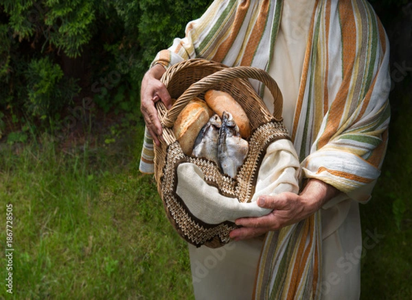 Obraz Man holding a basket with fish and bread