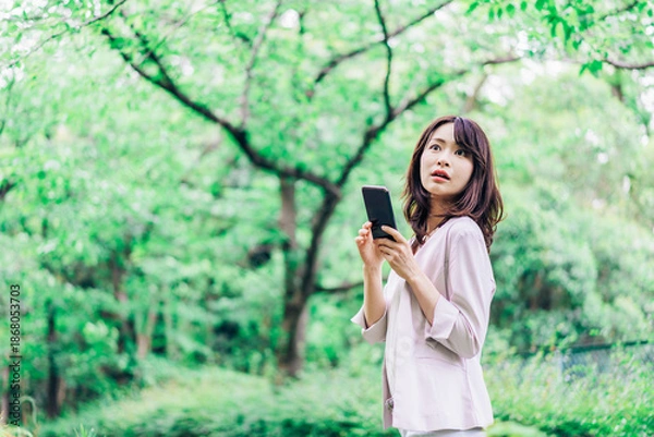 Obraz 外でスマホを使うビジネスウーマン