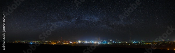 Fototapeta Panoramiczny widok na rozgwieżdżone nocne niebo nad miastem.