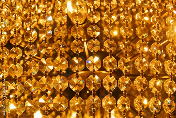 Fototapeta Bright golden gold yellow shiny abstract pattern, close up of details of a big beautiful luxury crystal chandelier, abstract indoor background with blur bokeh at the background.