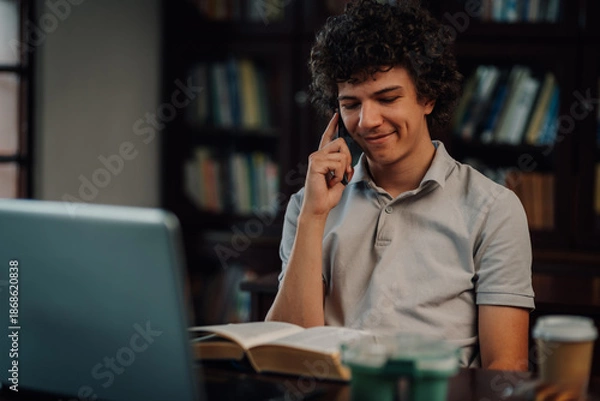Obraz Student talking on smartphone while studying in library
