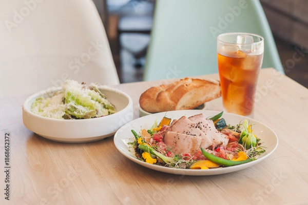 Obraz テーブルに並ぶ肉料理とサラダと飲み物の食事風景