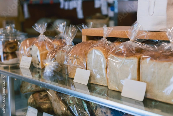 Obraz 包装された食パンが並ぶベーカリーの店内風景