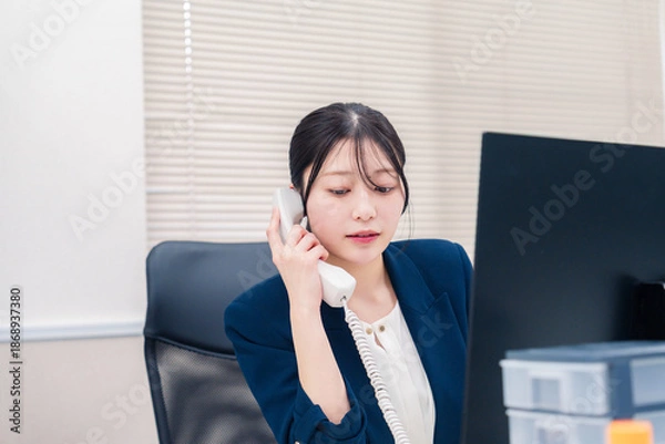 Obraz オフィスの固定電話で通話をする女性ビジネスパーソン