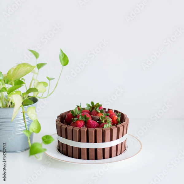 Obraz A chocolate cake with kitkat and strawberry on white desk. A very delicious cake.