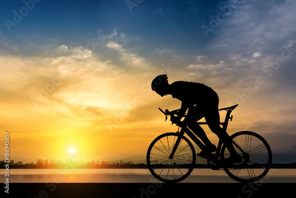 Fototapeta Silhouette of man ride a bicycle in sunset background